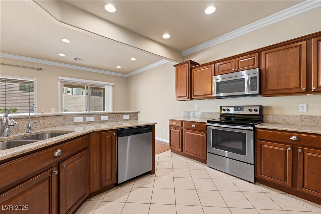 1551 Watchmans Point Mesquite, NV 89034 - Photo 24 of 62 Kitchen featuring appliances with stainless steel finishes, ornamental molding, light stone counters, light tile patterned floors, and recessed lighting