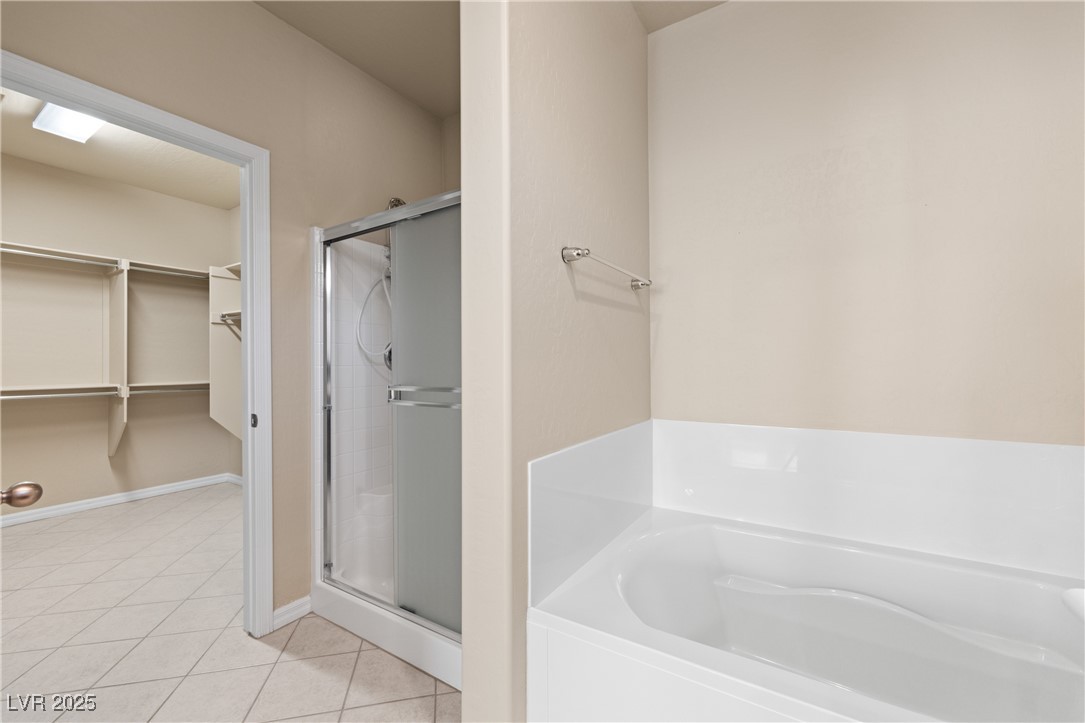1551 Watchmans Point Mesquite, NV 89034 - Photo 33 of 62 Bathroom featuring a stall shower, light tile patterned flooring, a bath, and a spacious closet