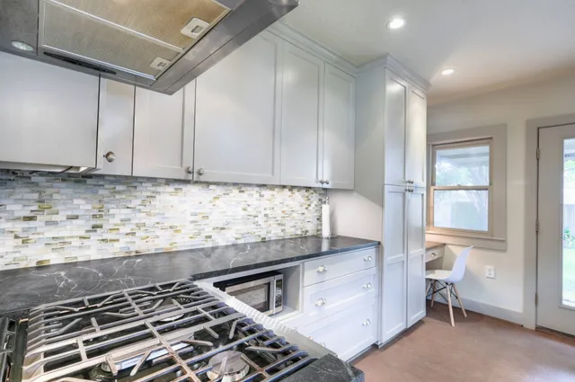 a kitchen with granite countertop a sink a stove and cabinets