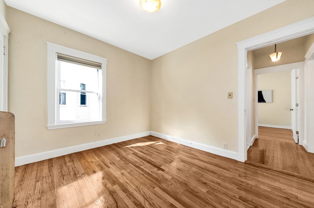 34 Harvard Street, Unit 1 Arlington, MA 02476 - Photo 16 of 36 a view of an empty room with wooden floor and a window