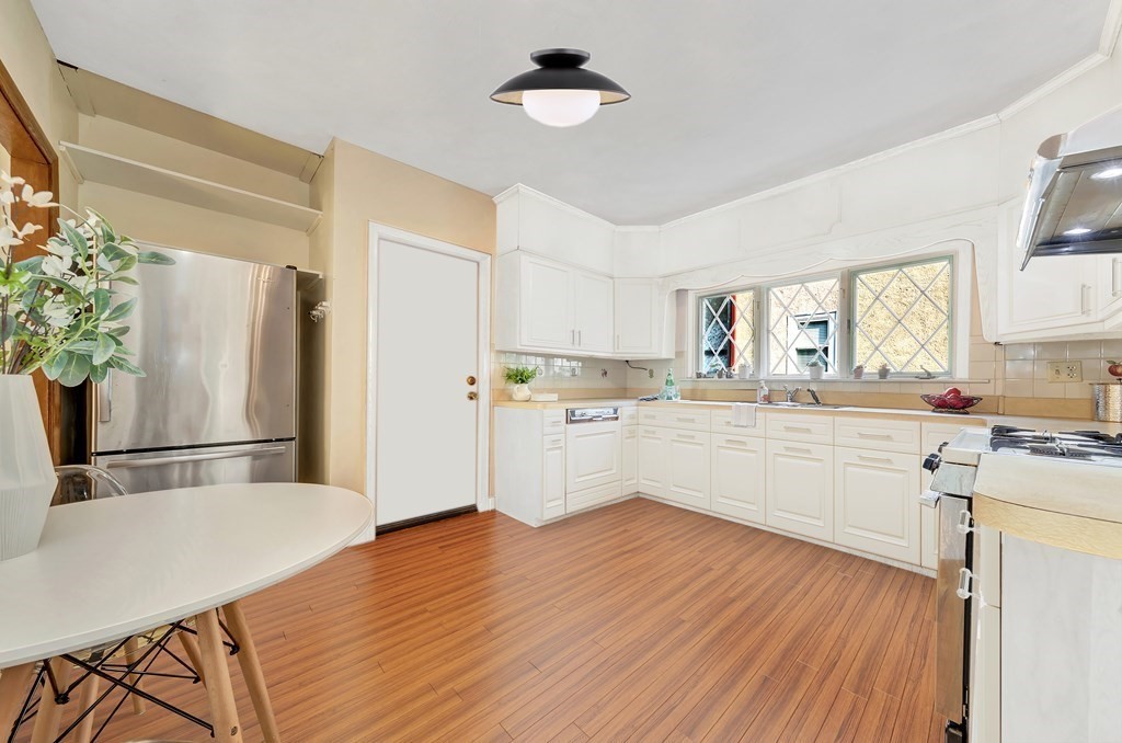 34 Harvard Street, Unit 1 Arlington, MA 02476 - Photo 26 of 36 a kitchen with granite countertop a refrigerator a stove a sink dishwasher and white cabinets with wooden floor