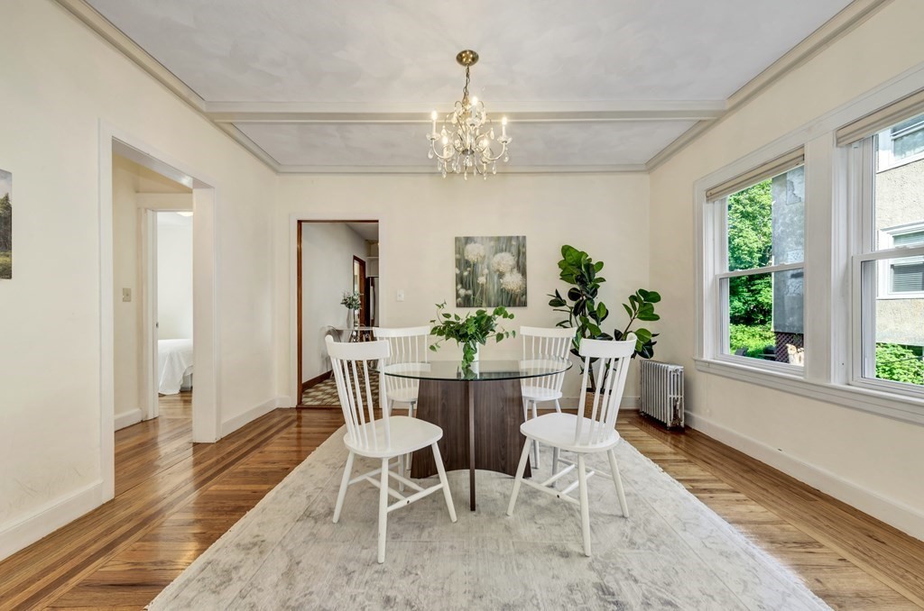34 Harvard Street, Unit 1 Arlington, MA 02476 - Photo 10 of 36 a dining room with wooden floor a chandelier a wooden table and chairs