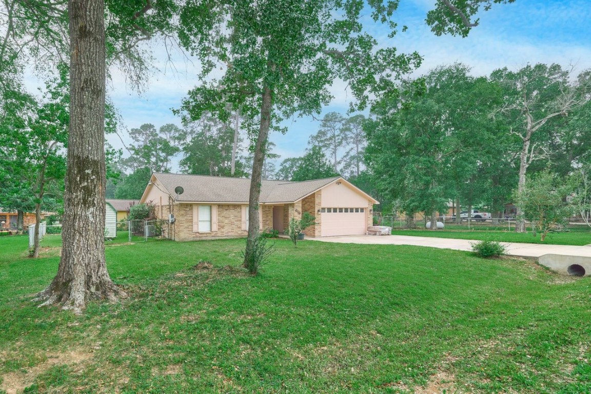 619 Pinewood Drive Conroe, TX 77385 - Photo 2 of 44 a view of a house with a yard and a large tree