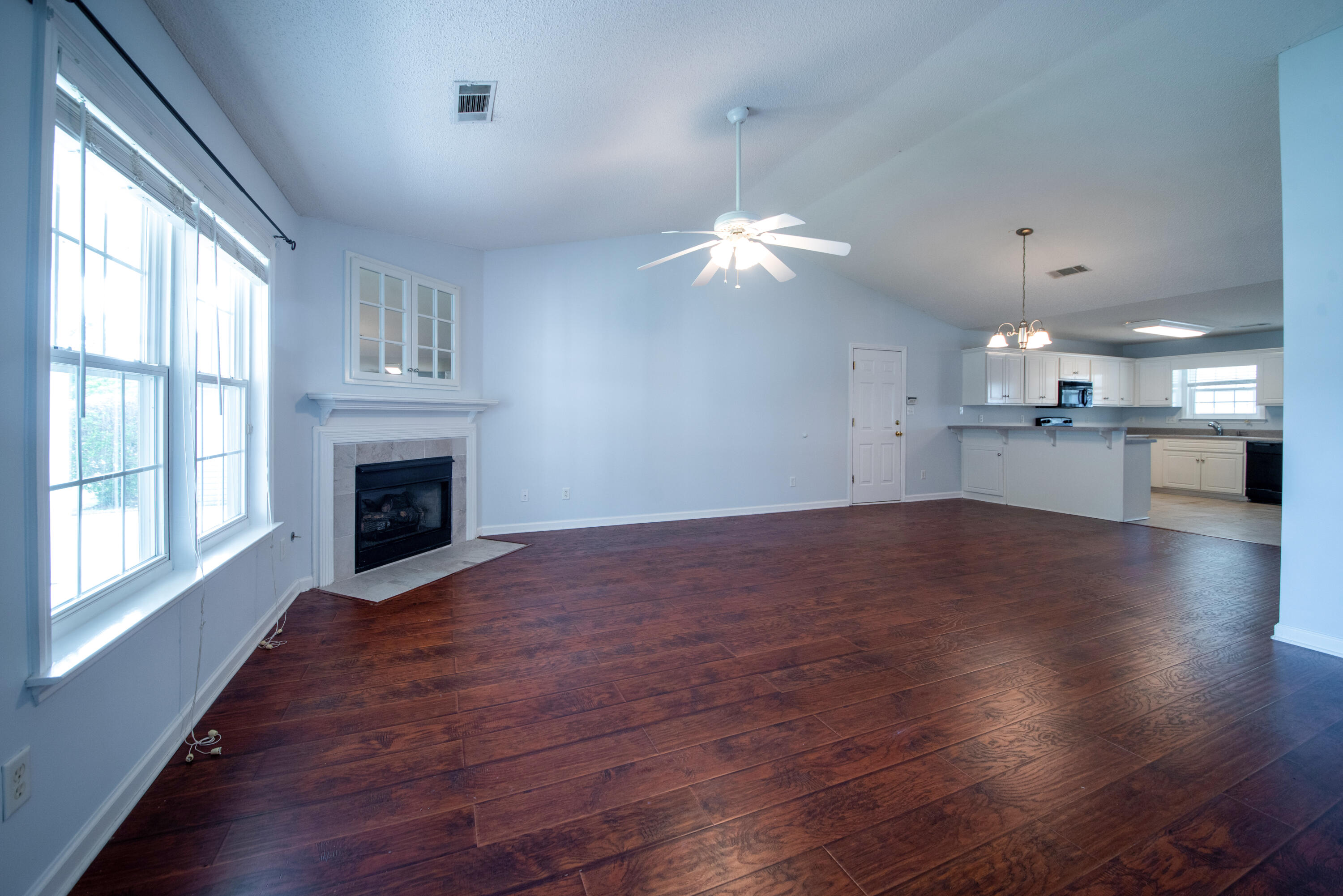 8 Chappells Road Aiken, SC 29803 - Photo 3 of 15 an empty room with wooden floor fireplace and a kitchen