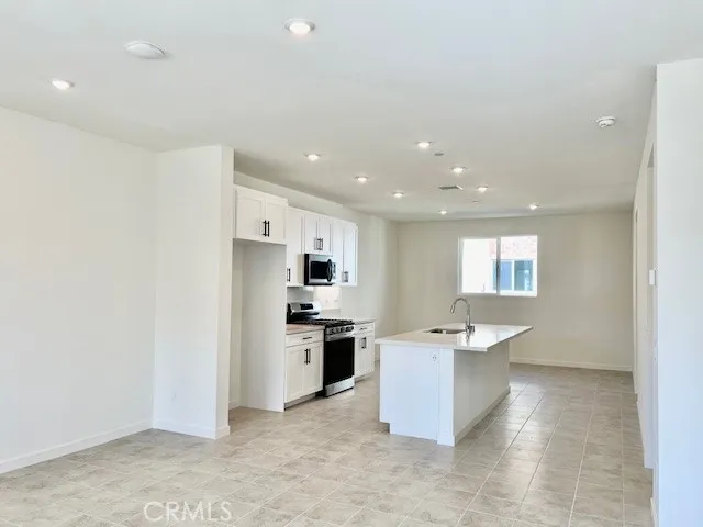 a room with stainless steel appliances kitchen island granite countertop a refrigerator and a stove top oven