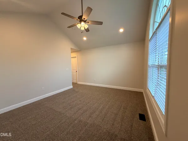an empty room with a chandelier fan and windows