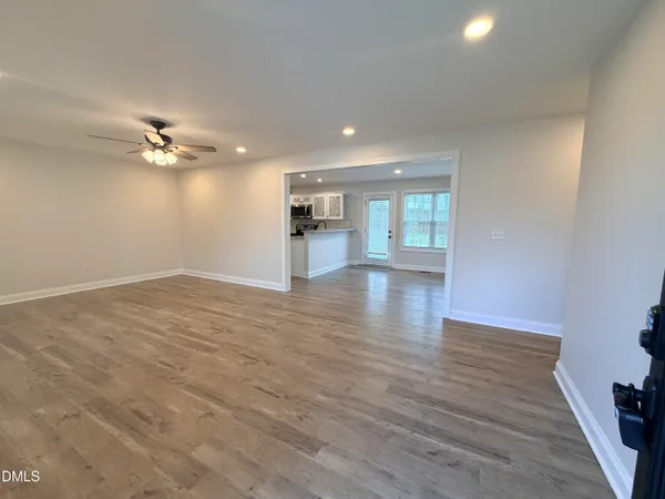 a view of an empty room with a window and wooden floor