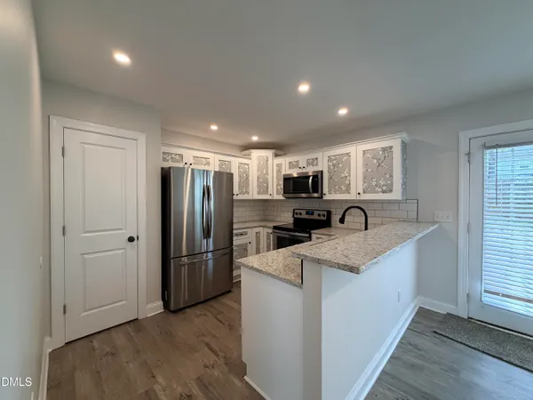 a kitchen with granite countertop a refrigerator a sink a stove and cabinets
