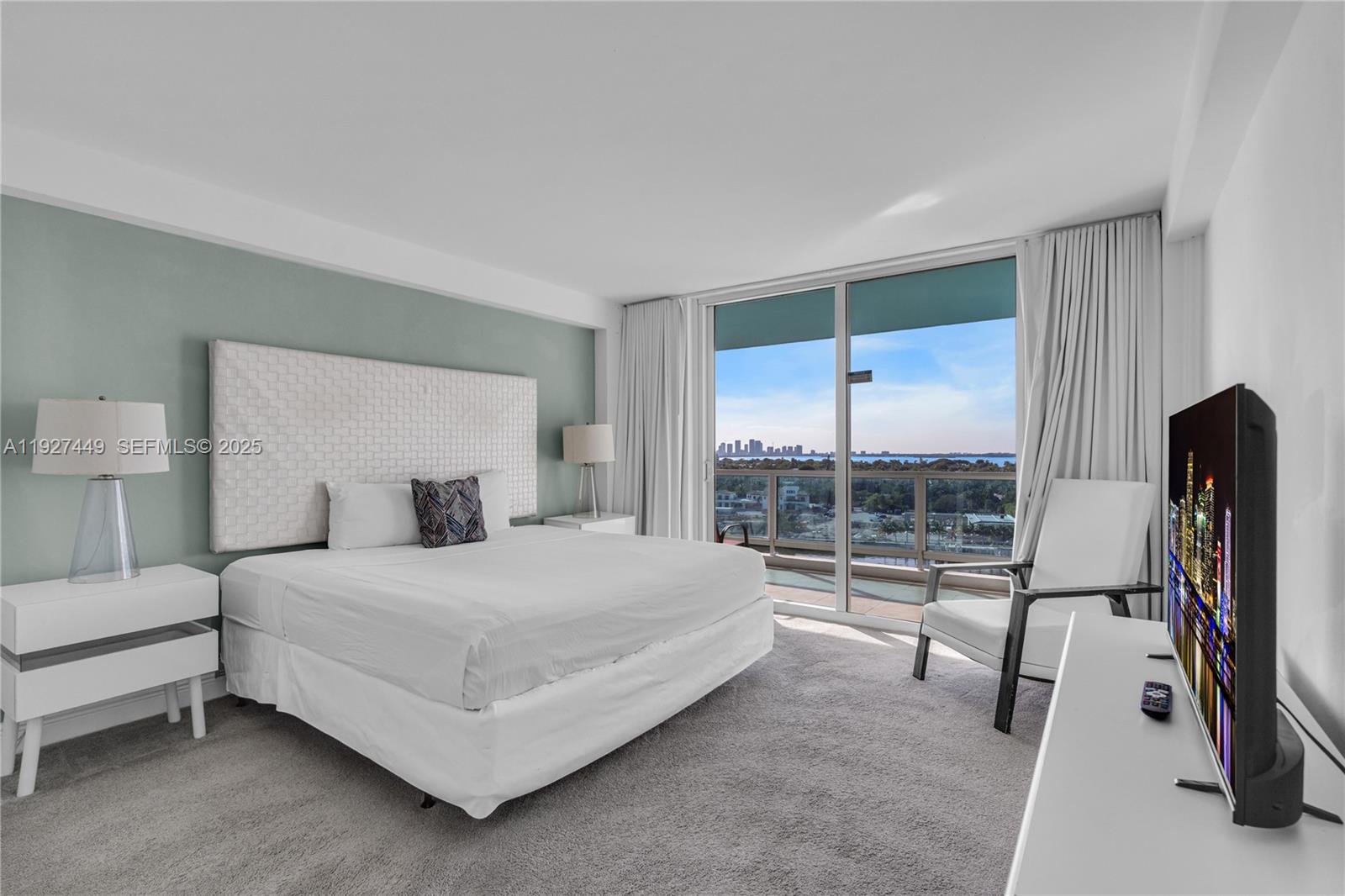 5101 Collins Avenue, Unit 12R Miami Beach, FL 33140 - Photo 5 of 13 a bedroom with a bed and a flat tv screen next to a window