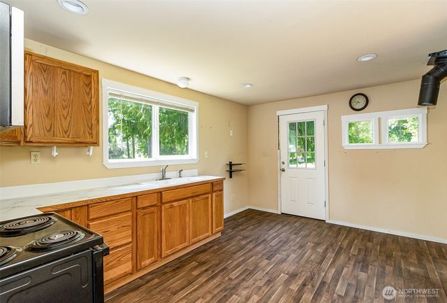 a view of a kitchen with wooden floor and stainless steel appliances
