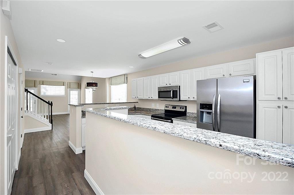 11630 Rabbit Ridge Road Charlotte, NC 28270 - Photo 4 of 32 a kitchen with stainless steel appliances granite countertop a refrigerator a sink dishwasher a stove and a wooden floor