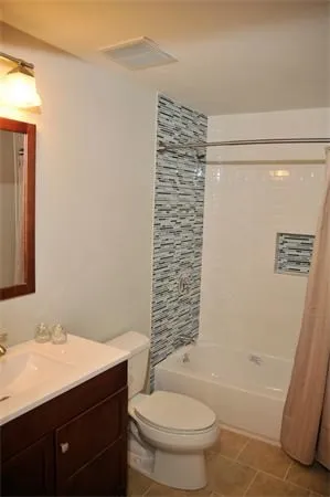 a bathroom with a bathtub shower sink vanity and toilet