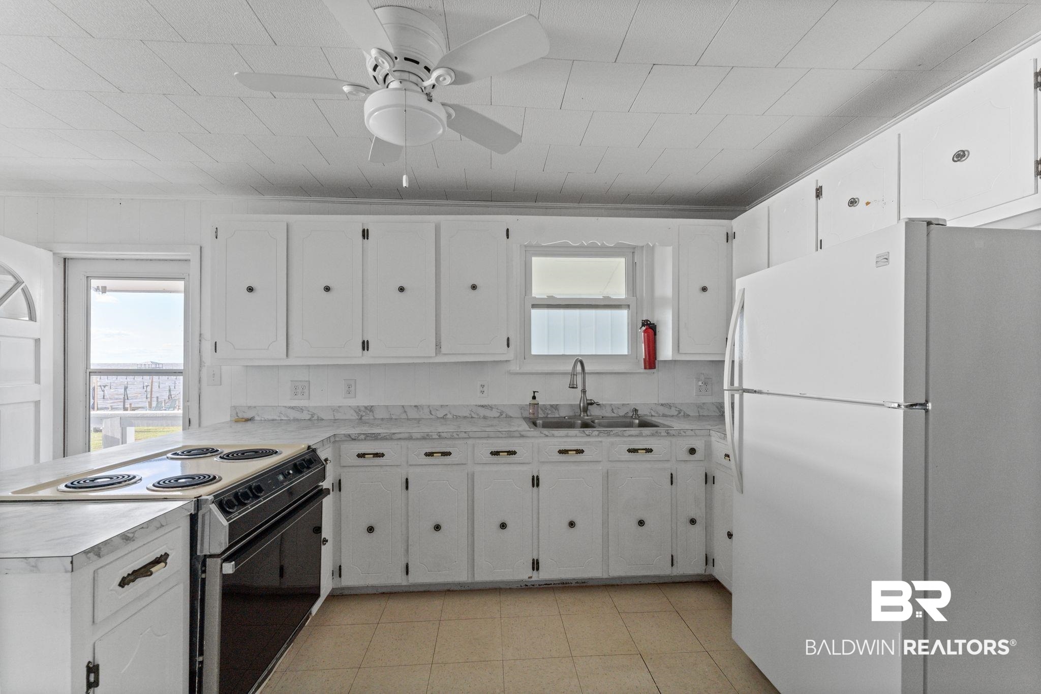 8959 Shore Drive Foley, AL 36535 - Photo 25 of 53 Kitchen featuring freestanding refrigerator, range with electric cooktop, light countertops, and white cabinets