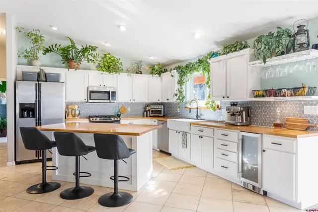 a kitchen with stainless steel appliances kitchen island granite countertop a table chairs sink and cabinets