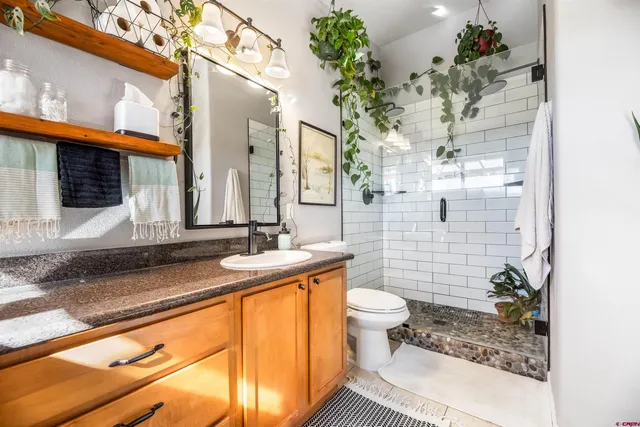 a bathroom with a granite countertop sink a toilet and mirror