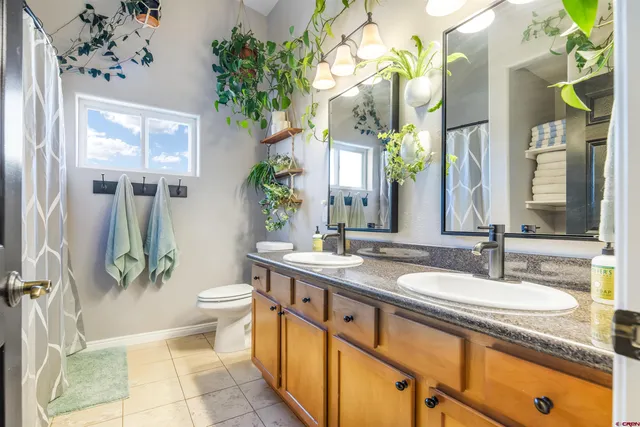 a spacious bathroom with a granite countertop sink a toilet a mirror a vanity and a shower