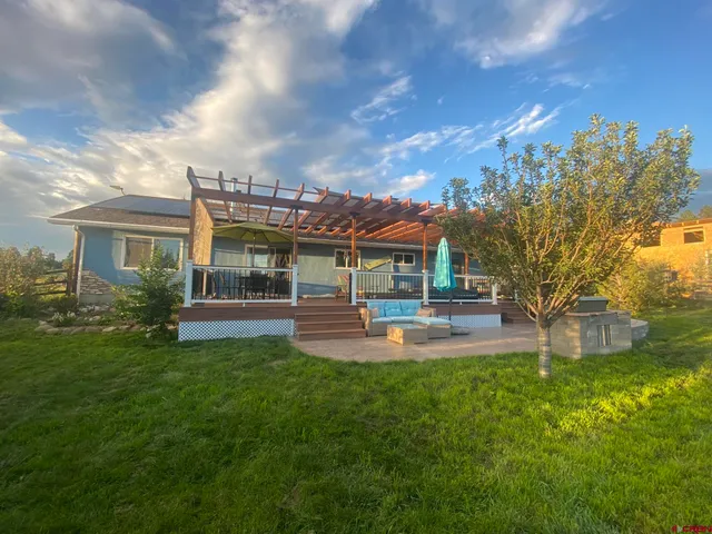 a view of a house with a big yard potted plants and large tree