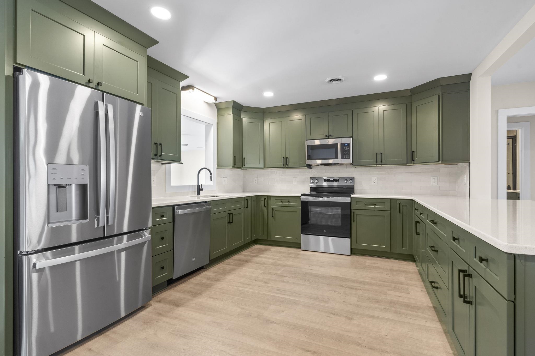 947 Fox Hollow Road Conway, SC 29526 - Photo 16 of 40 Kitchen featuring green cabinetry, stainless steel appliances, light wood-style floors, a peninsula, and decorative backsplash