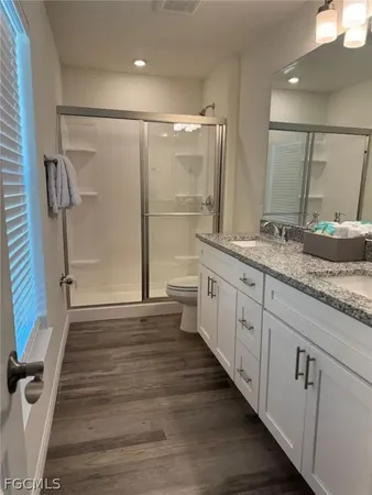 a spacious bathroom with a granite countertop sink a toilet a mirror and shower