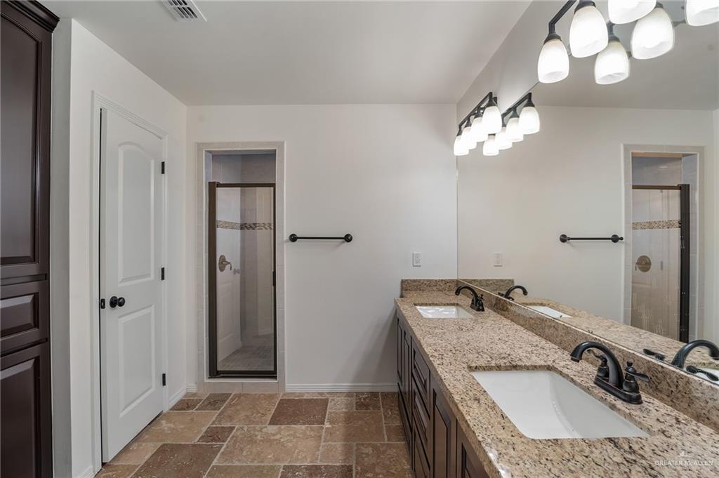 6707 South Rios Street Pharr, TX 78577 - Photo 10 of 17 a bathroom with a granite countertop sink a light fixture and a mirror
