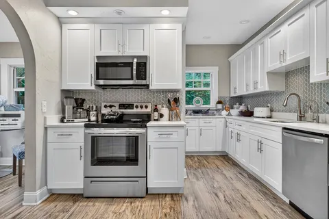 a kitchen with stainless steel appliances granite countertop a stove microwave and sink