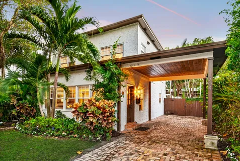 a view of a house with potted plants and a large tree
