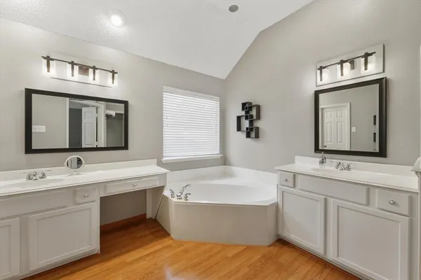 a bathroom with a tub double sink window and mirror