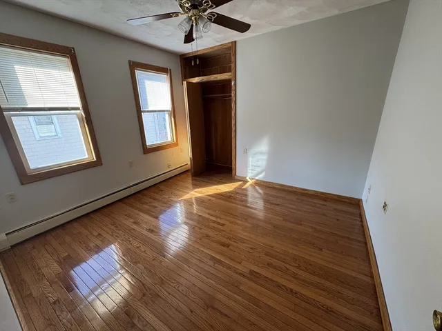 a view of an empty room with a window and wooden floor