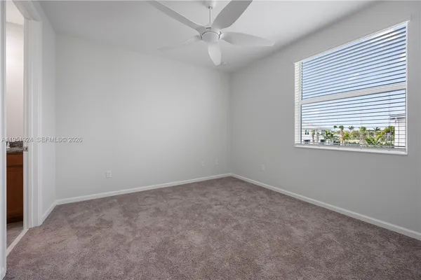 an empty room with a window and ceiling fan