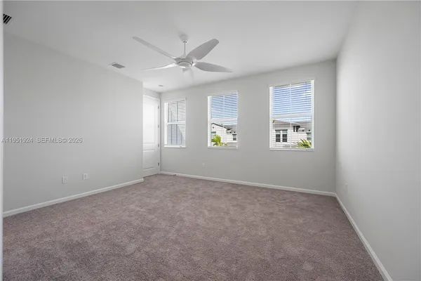 an empty room with windows and fan