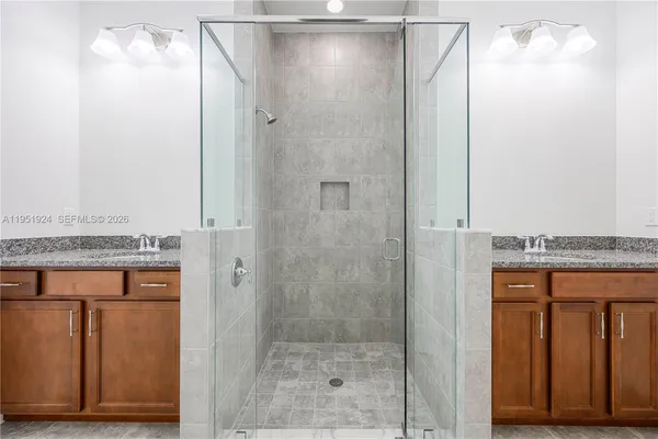 a bathroom with a granite countertop shower a mirror and a sink