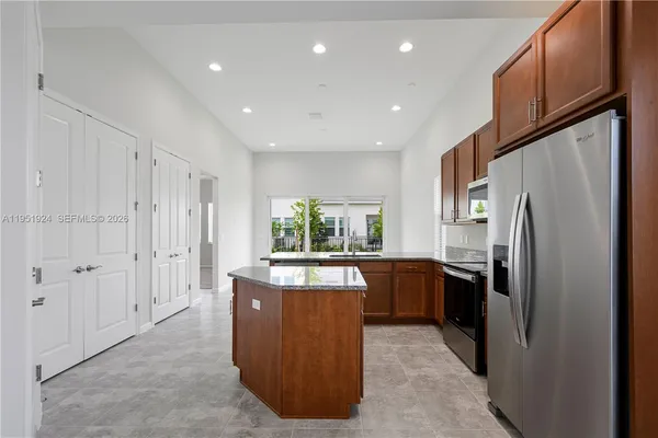 a large kitchen with stainless steel appliances granite countertop a refrigerator and a stove