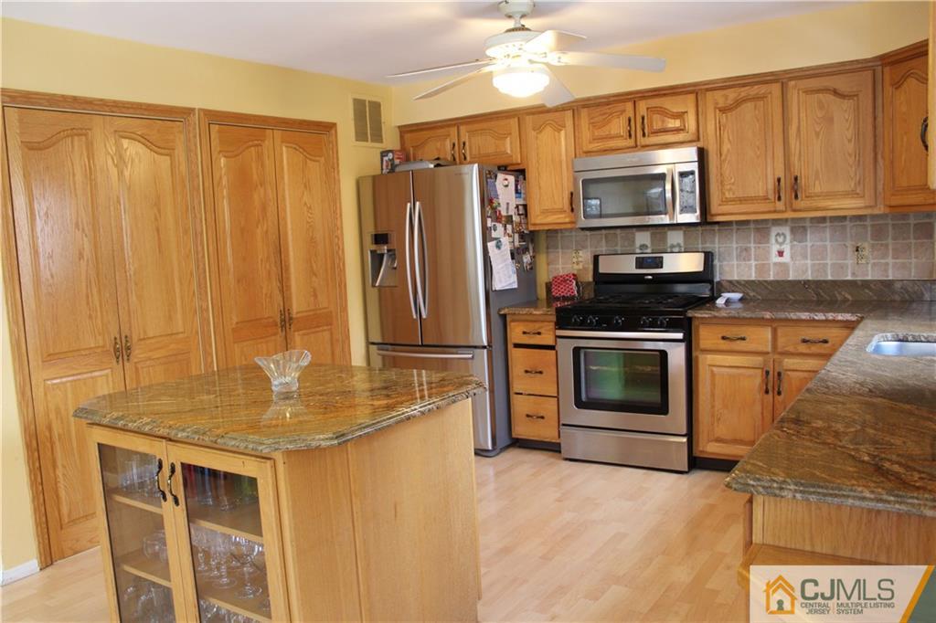 4901 Stonehedge Road, Unit 4901 Edison, NJ 08820 - Photo 8 of 22 a kitchen with stainless steel appliances granite countertop a stove a sink dishwasher and a refrigerator with wooden cabinet