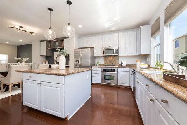 a large white kitchen with a large island oven a stove and white cabinets