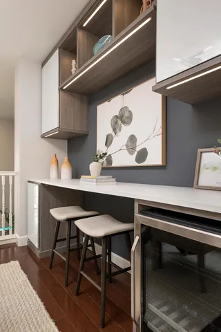 a kitchen with stainless steel appliances granite countertop a refrigerator a sink dishwasher a stove and a dining table with wooden floor