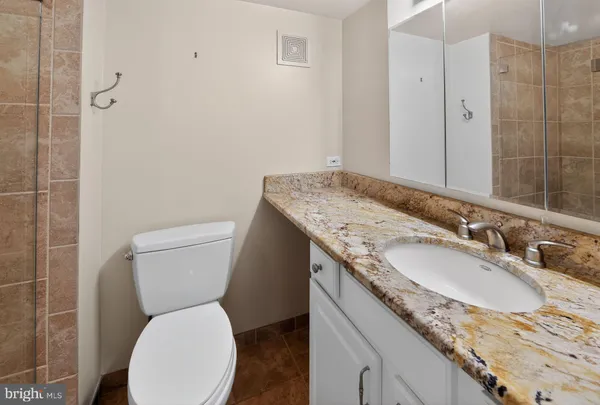 a bathroom with a granite countertop toilet sink and mirror