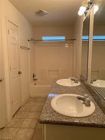 a bathroom with a granite countertop sink a mirror and shower