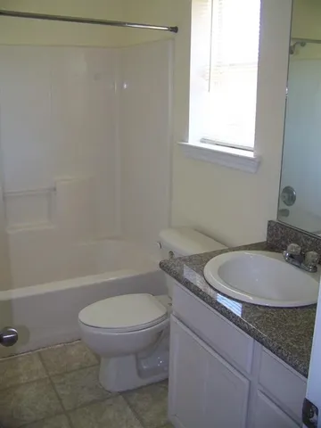 a bathroom with a granite countertop toilet a sink and a mirror