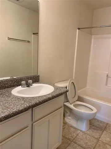 a bathroom with a granite countertop sink toilet and a mirror
