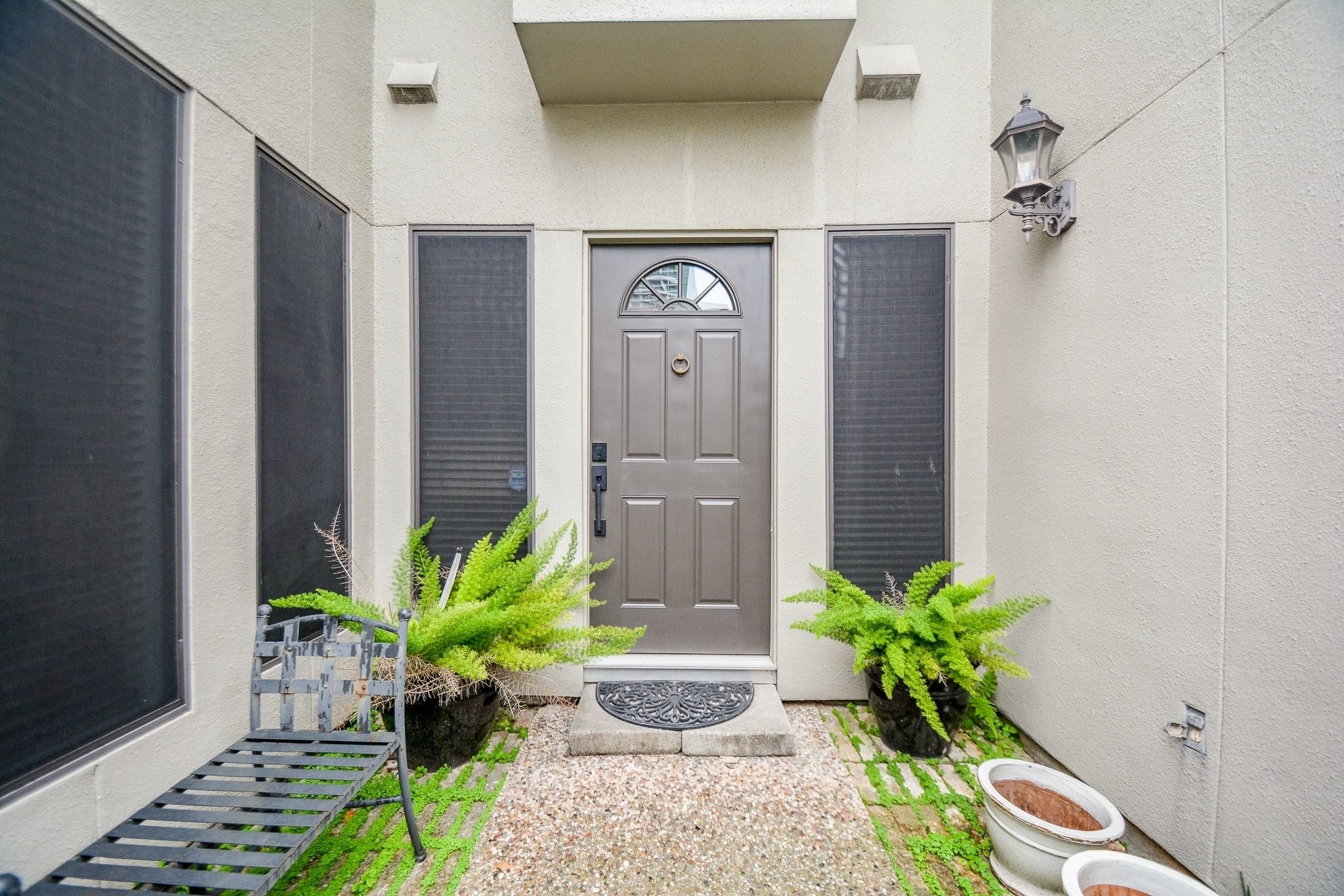 A private gated entry courtyard sets the tone, framed by lush ferns and a charming bench just outside the front door.