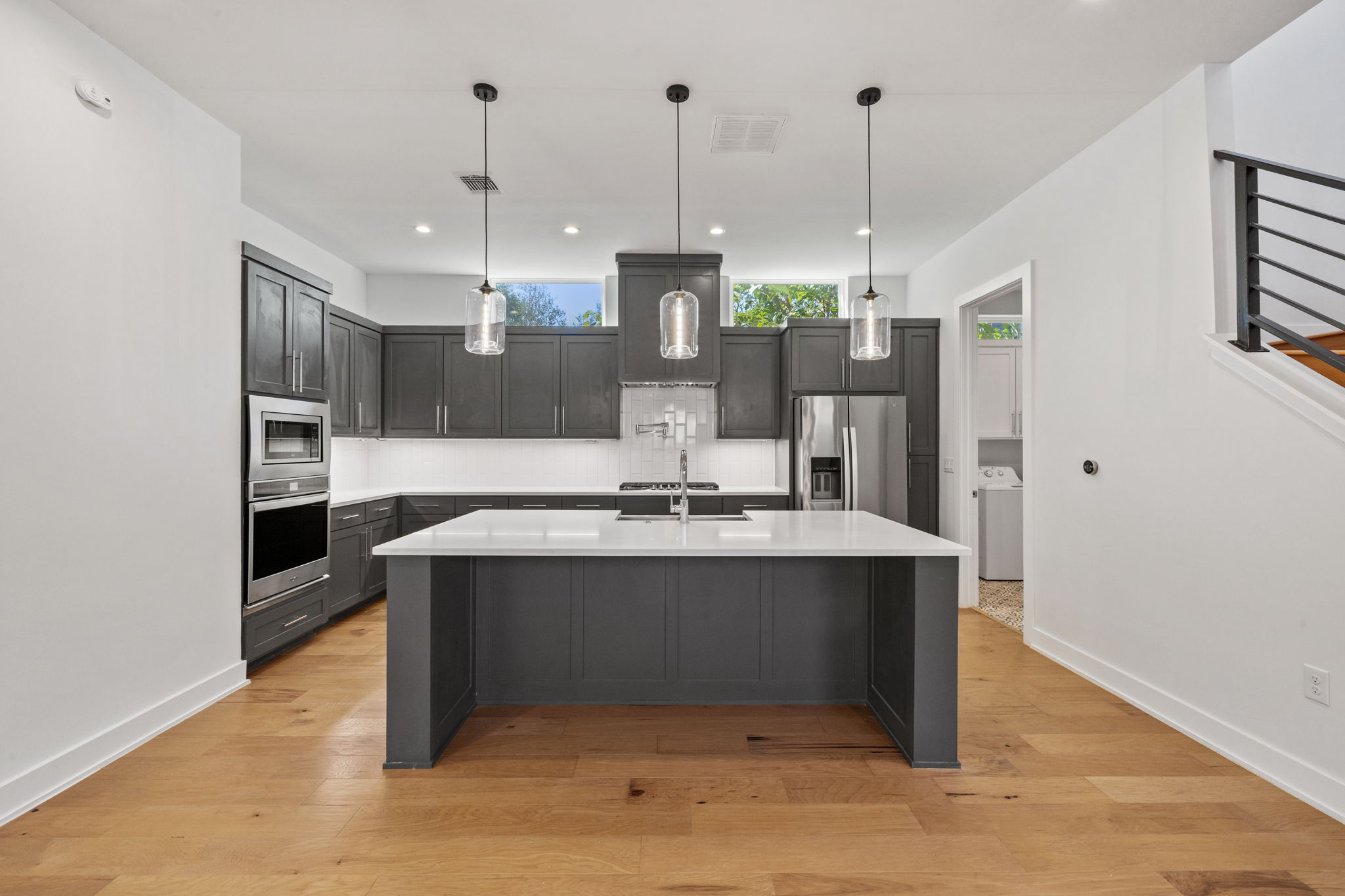 1719 Bunche Road Austin, TX 78721 - Photo 12 of 36 Rich hardwood flooring anchors this modern culinary space featuring a generous prep island.