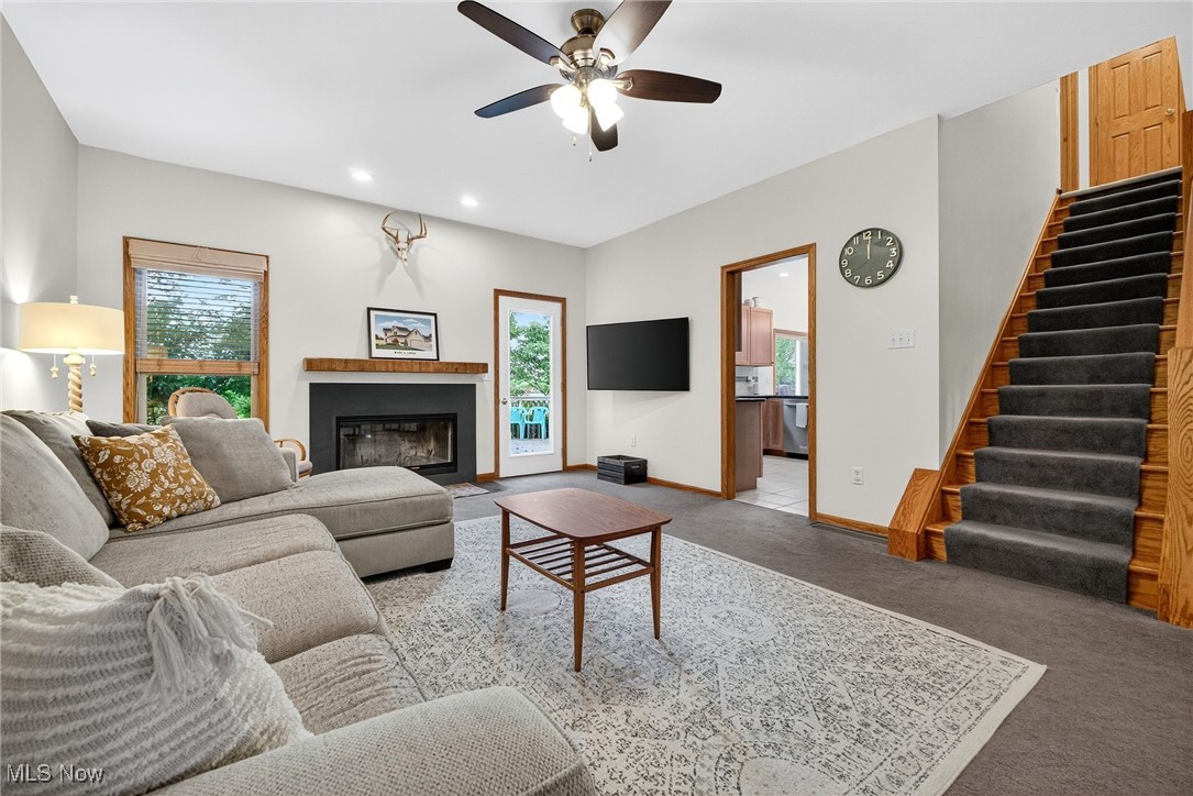 35748 Mills Road Avon, OH 44011 - Photo 11 of 44 Carpeted living area featuring stairs, plenty of natural light, a ceiling fan, a fireplace with flush hearth, and recessed lighting