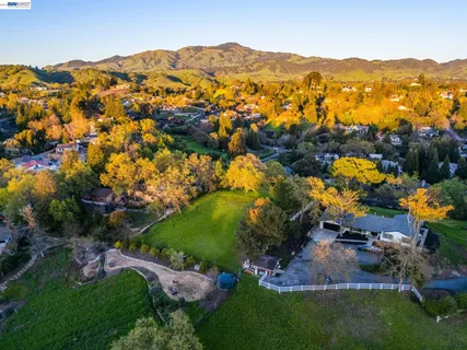 an aerial view of a residential houses with outdoor space and trees all around