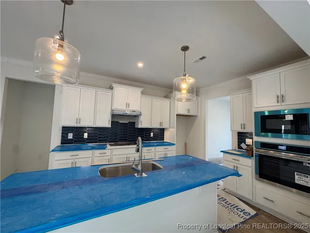 a kitchen with stainless steel appliances granite countertop a sink a stove and a wooden floors