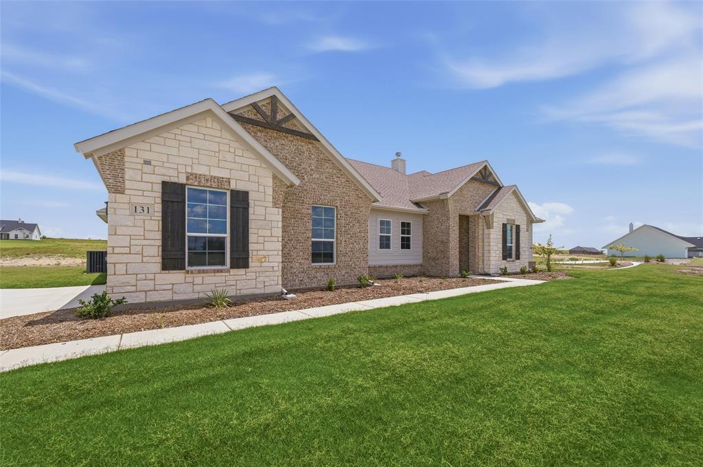 131 Big Sky Road Decatur, TX 76234 - Photo 3 of 23 Stone and brick exterior with dark window shutters, gabled rooflines, and a concrete walkway