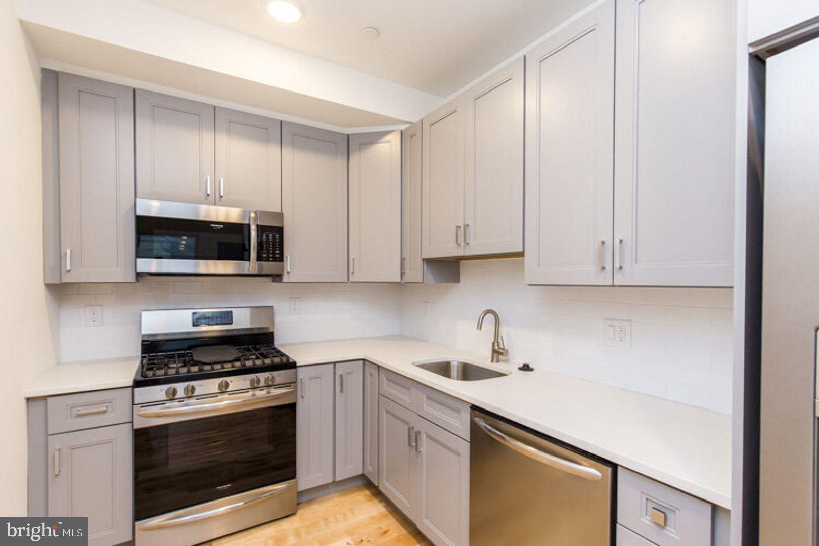a kitchen with granite countertop white cabinets and stainless steel appliances
