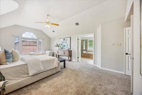 a spacious bedroom with a bed a table and painting on the wall