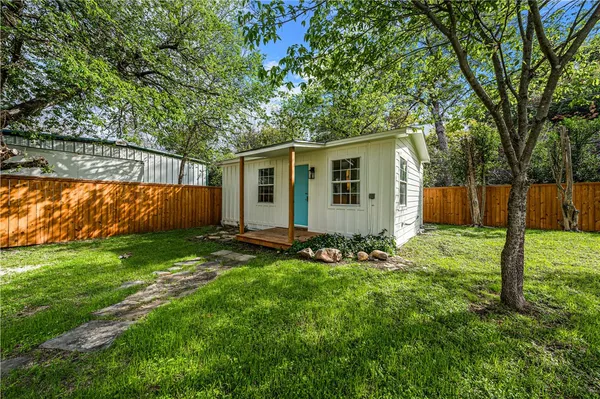 a view of a backyard with table and chairs and large tree
