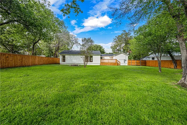 a view of a yard in front of a house with large trees