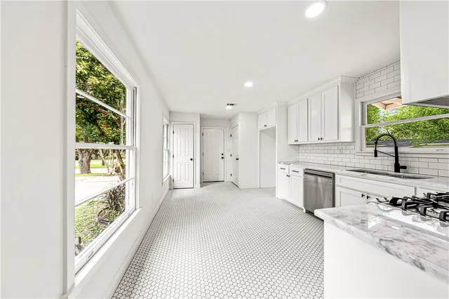 a kitchen with granite countertop white cabinets and stainless steel appliances